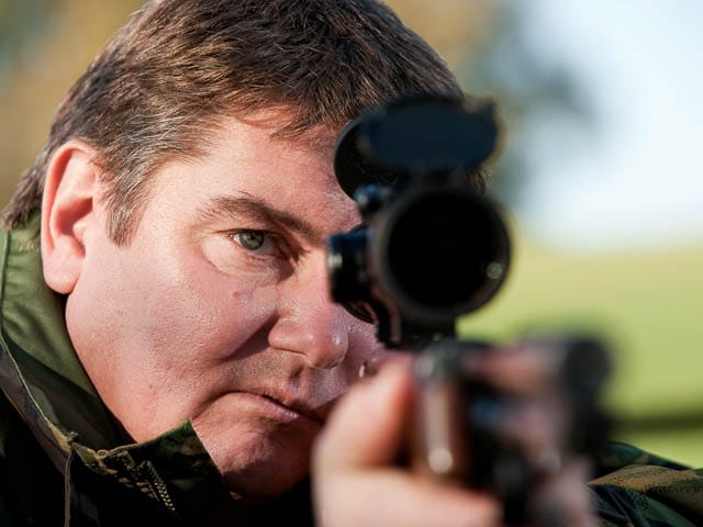 Air rifle marksman taking aim dressed in camouflage jacket
