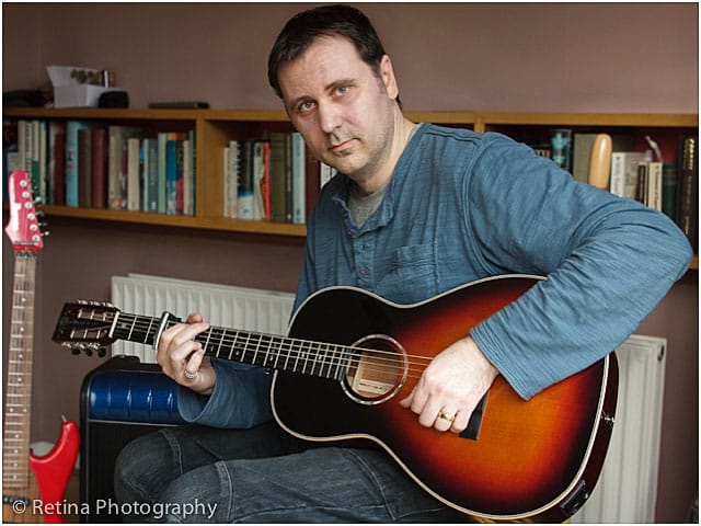 Seated Male Guitarist Playing Classical Guitar