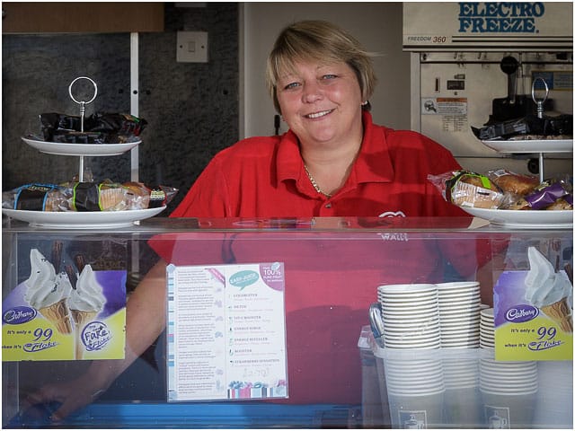 Portrait Of Charity Swimmer At The Counter Of Her Ice Cream Kiosk