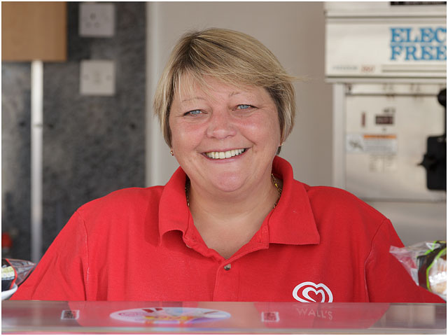 Portrait Of Ice Cream Kiosk Owner At Serving Counter Wearing Red Top
