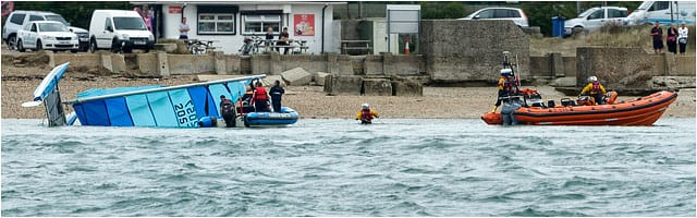 Rnli Crew In Water With Capsized Catamaran Boat