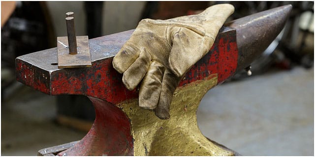 Blacksmiths glove laying on brightly coloured anvil Blacksmiths Glove Laying On Brightly Coloured Anvil