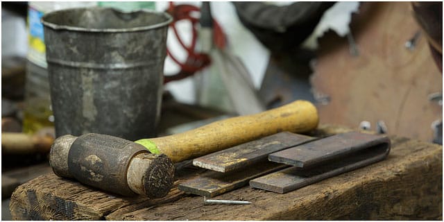 Hammer laying on wooden block in blacksmiths workshop Hammer Laying On Wooden Block In Blacksmiths Workshop
