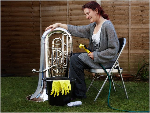 Female Tuba Player Cleaning E Flat Bass With Hose In Garden