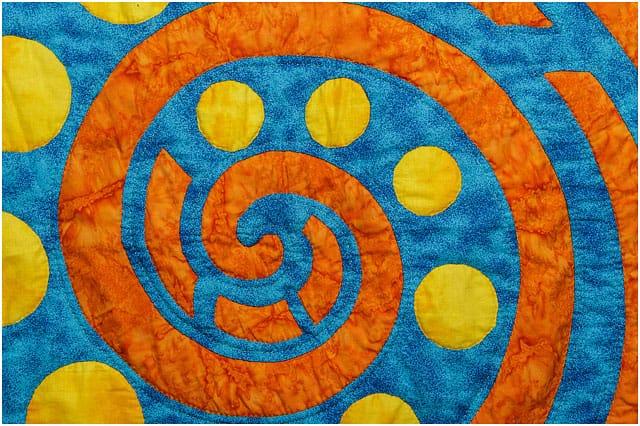 Quilt With Bright Orange Musical Swirl And Yellow Circles On Blue Background 