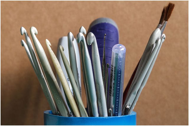 Collection Of Plastic Crochet Needles In Blue Plastic Cup 