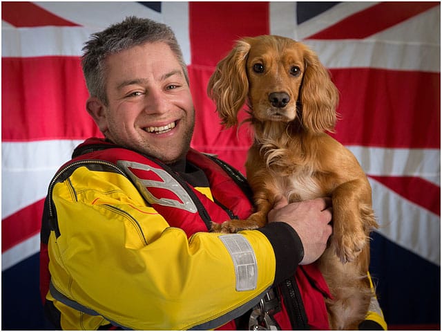 Portsmouth Rnli Crew Member and Pet Dog Working Cocker Spaniel with White Ensign Flag in Background