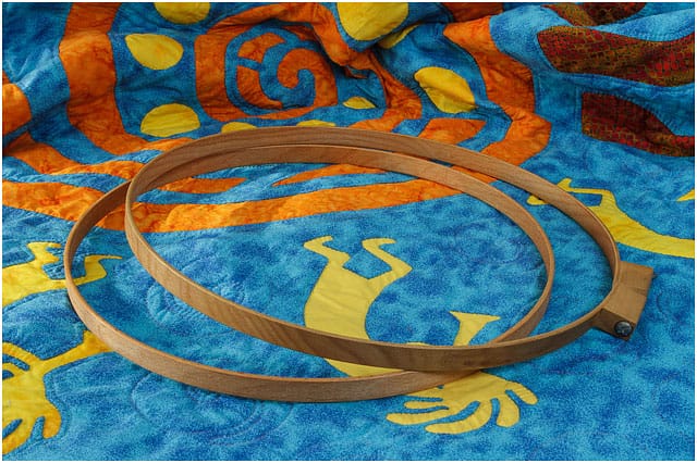 Wooden Quilting Hoops Laying On Large Blue Orange And Yellow Quilt 