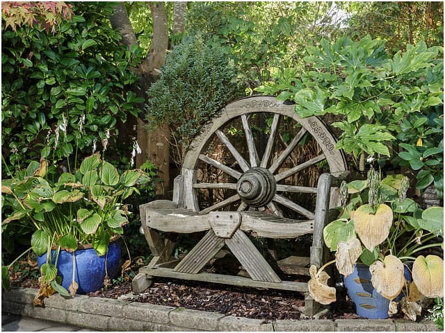 Wooden Wood Wagon Wheel Garden Seat Green Foliage Blue Pots 