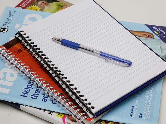 Writing Pad Blue Pen Stack of Magazines 