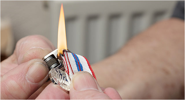 Sealing the edge of a medal ribbon with a lit cigarette lighter