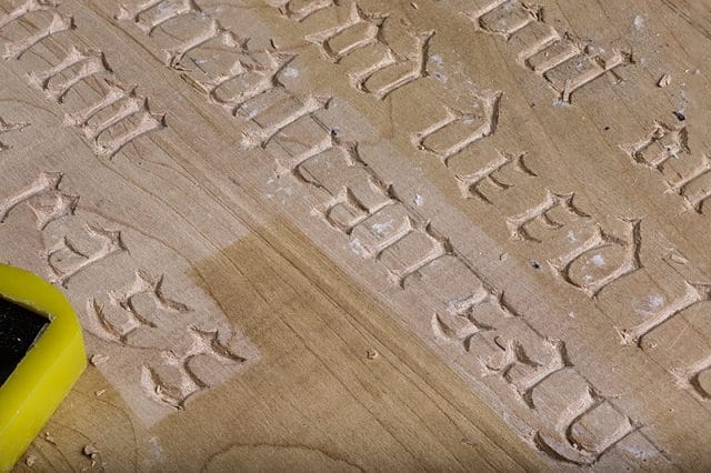 close up of hand carved gothic lettering plaque 