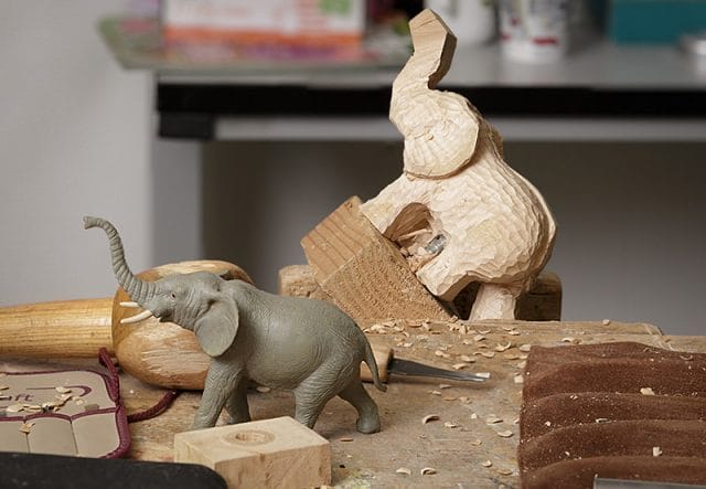 Close up of work in progress elephant carving with reference figure in the foreground 