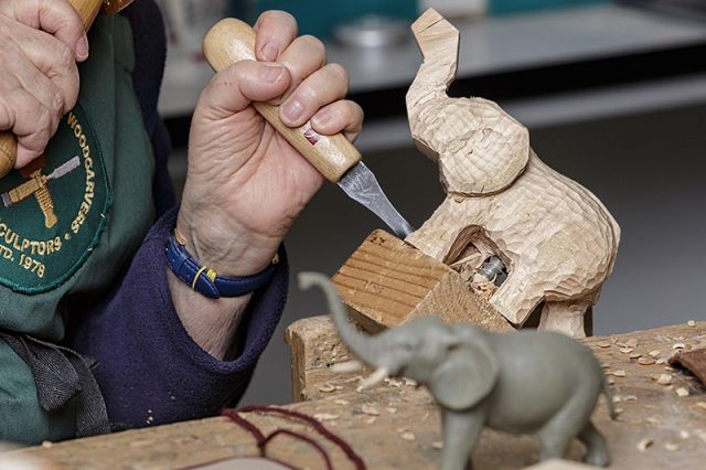 Close up of female woodcarver working on carving of an elephant 