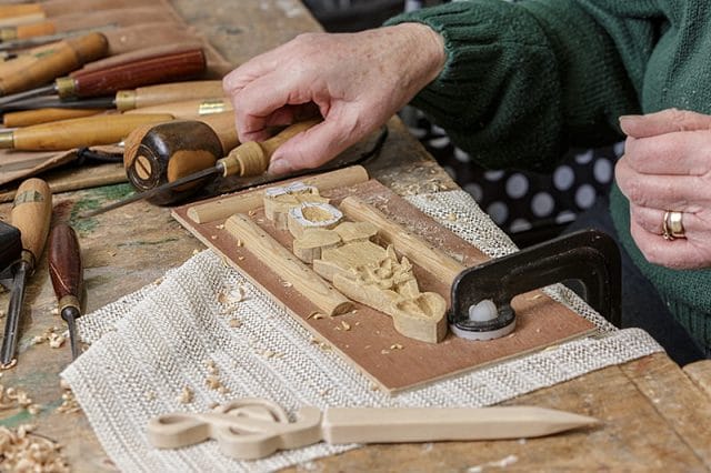 female woodcarver with carving project on workbench 