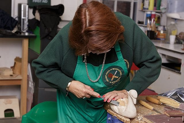 famale woodcarver carving a wooden swan 