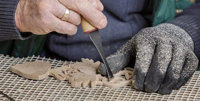 close up of male woodcarver and intricate carving 