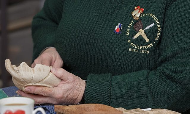 close up of female woodcarvers hands and work in progress carving 