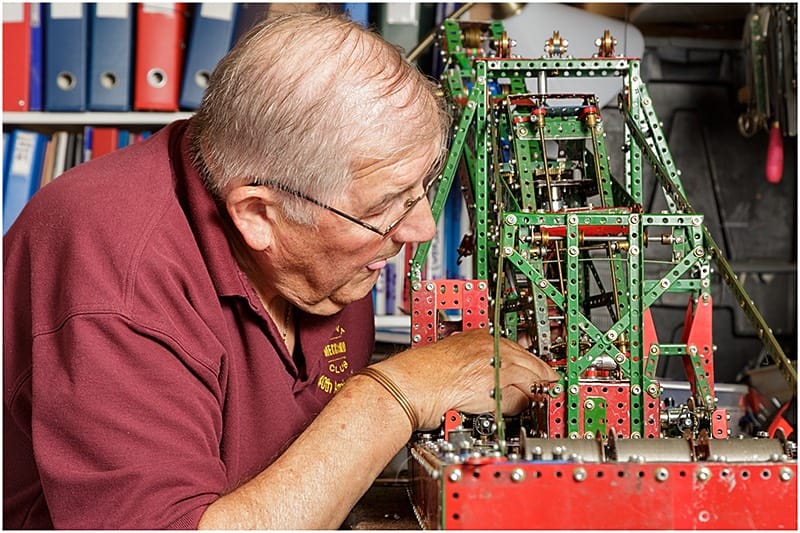 Meccano enthusiast building a model in his workshop