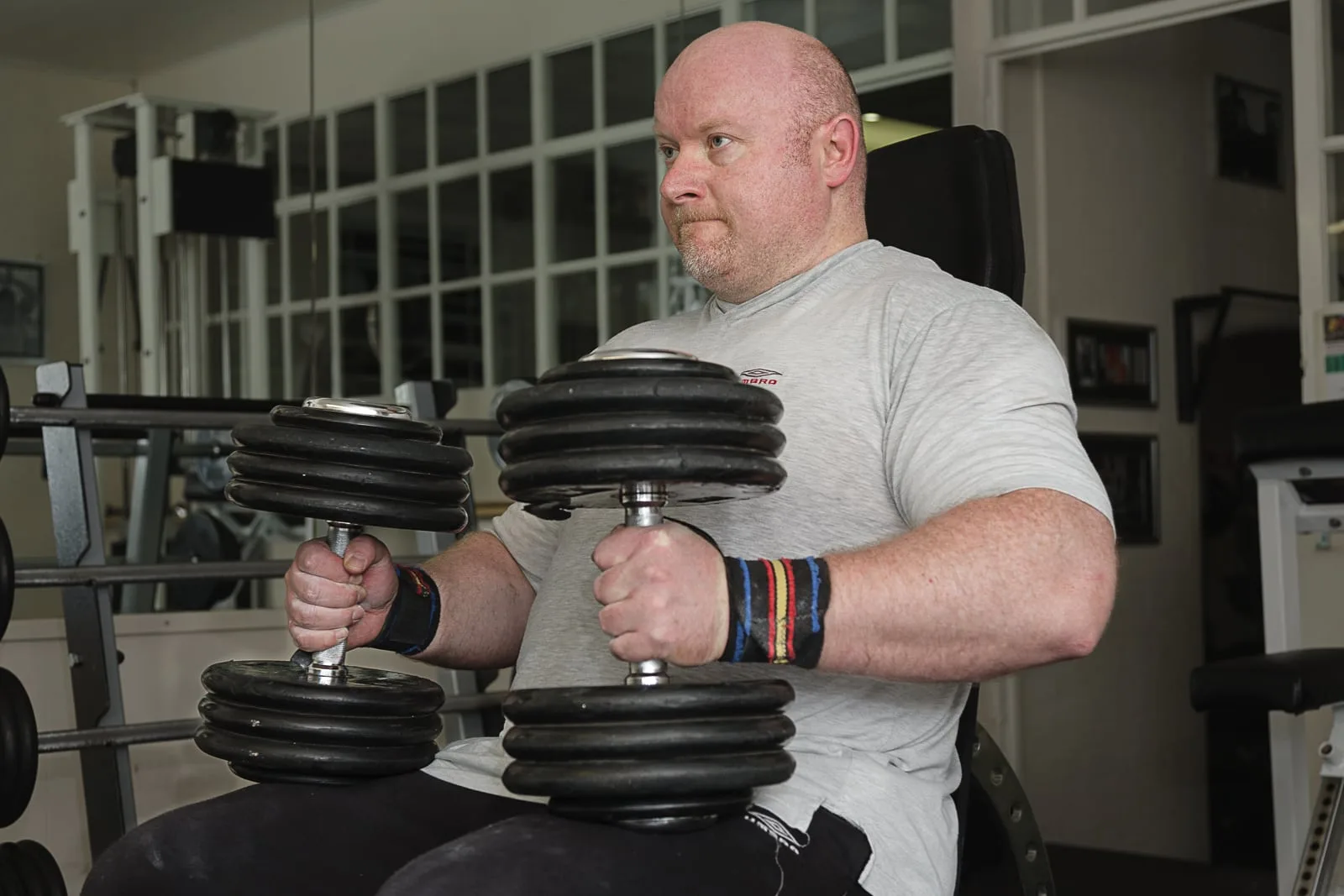 portrait of male powerlifter training in local gymnasium with large dumbbells