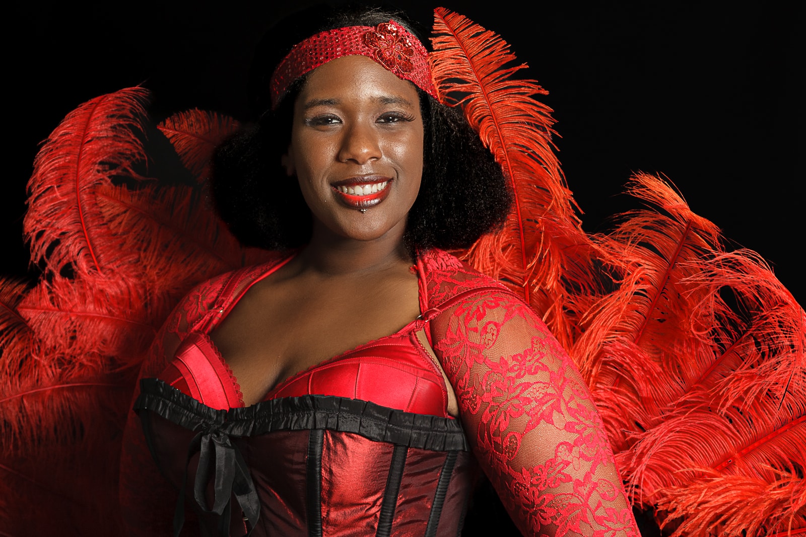 social media portrait of burlesque entertainer woman of colour in bright red outfit