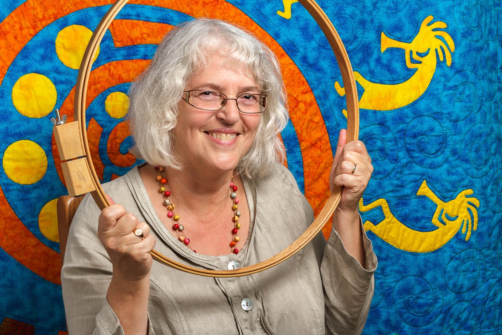 social media portrait of a middle aged woman and her quilting equipment and a brightly coloured rug