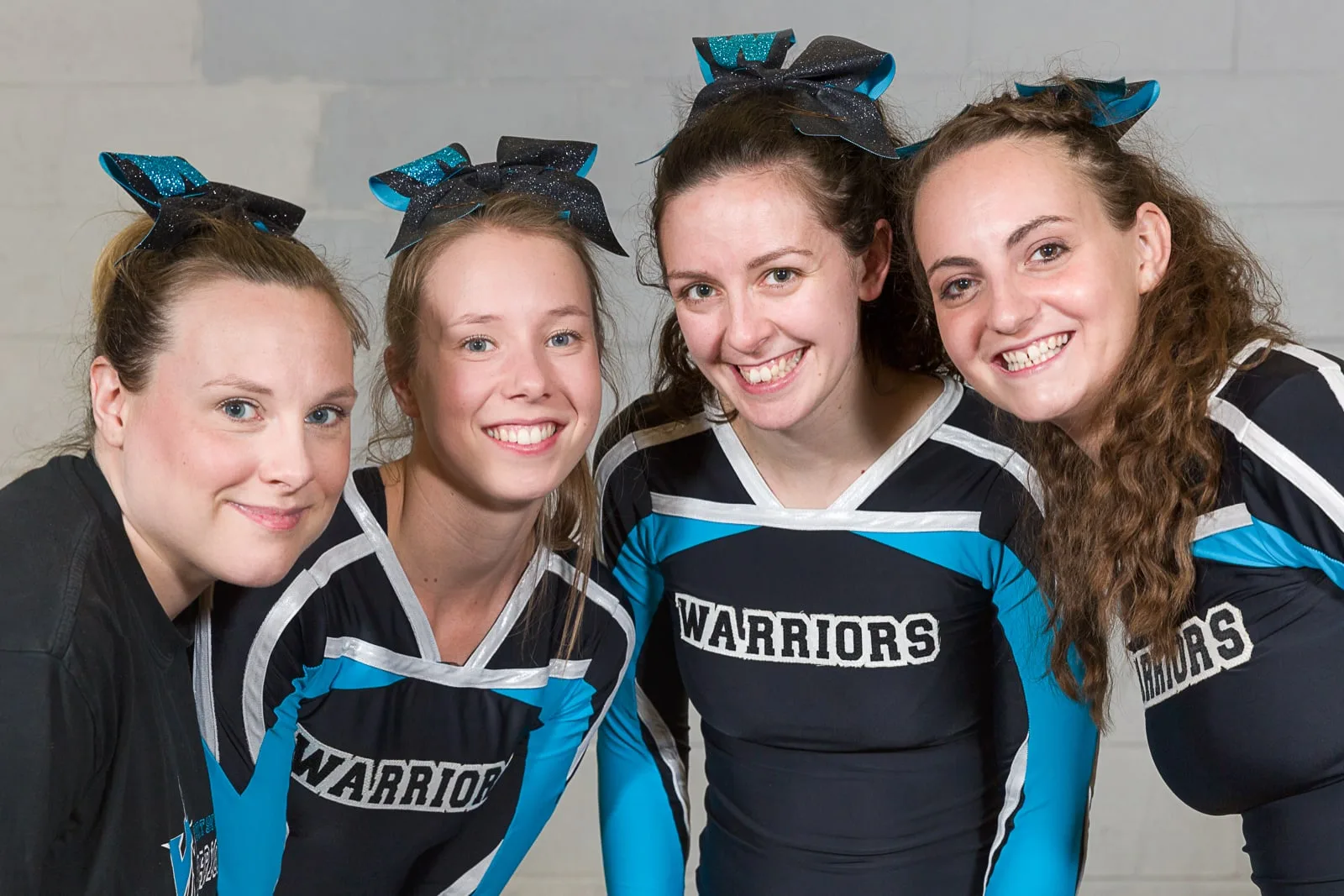 social media portrait of four young cheerleader trainers wearing branded costumes
