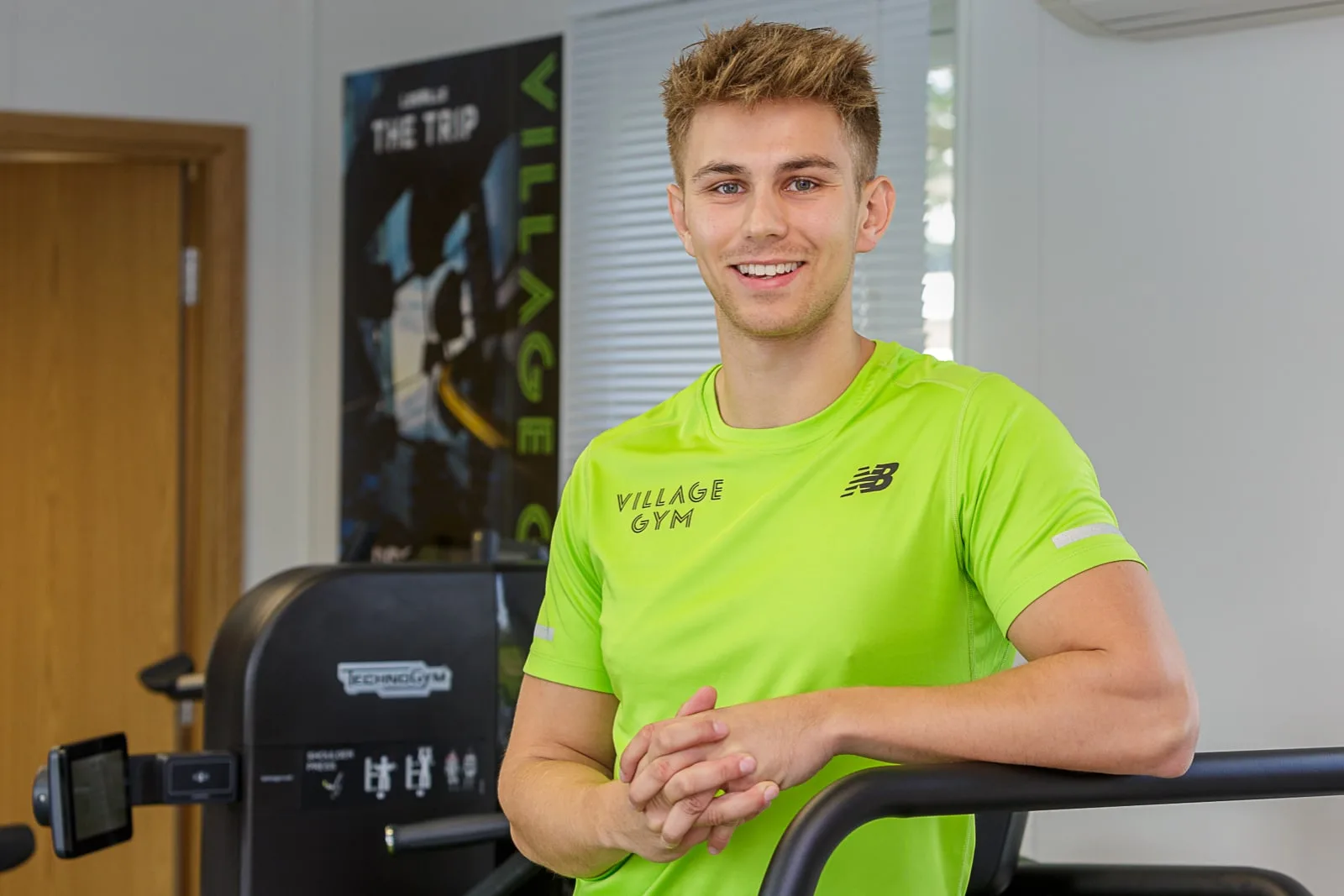 Business portrait of a young male health centre gym instructor wearing a lime green top
