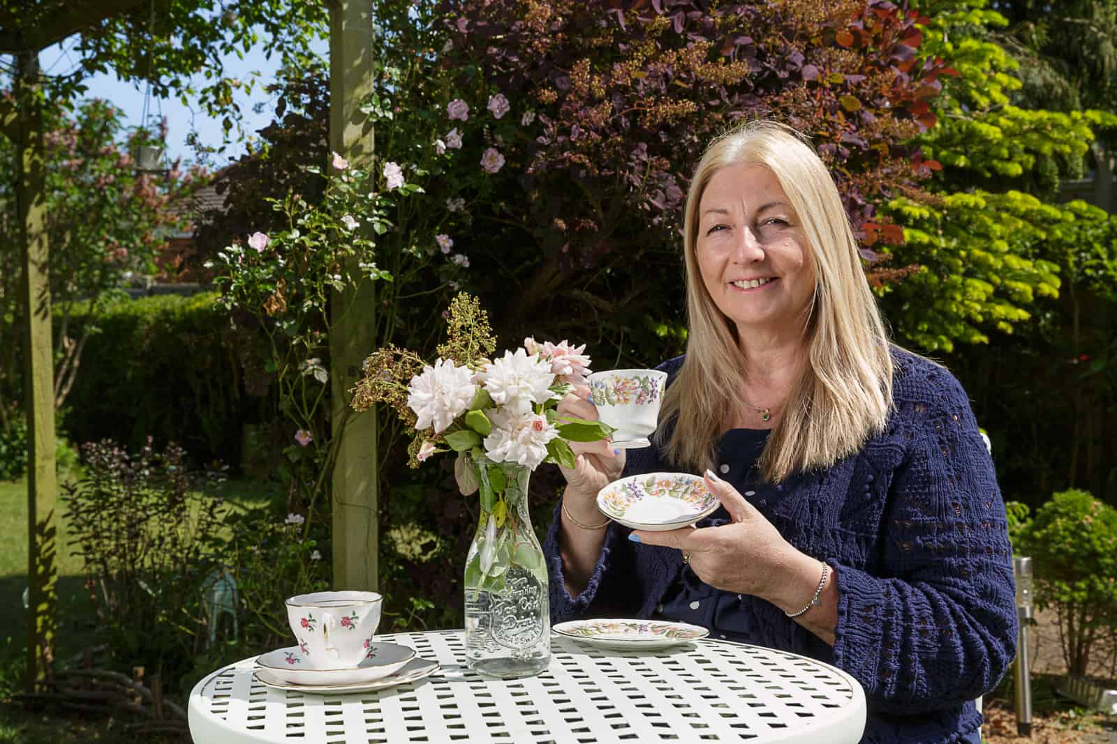 portrait of the owner of an english tea room sat in a sunny garden