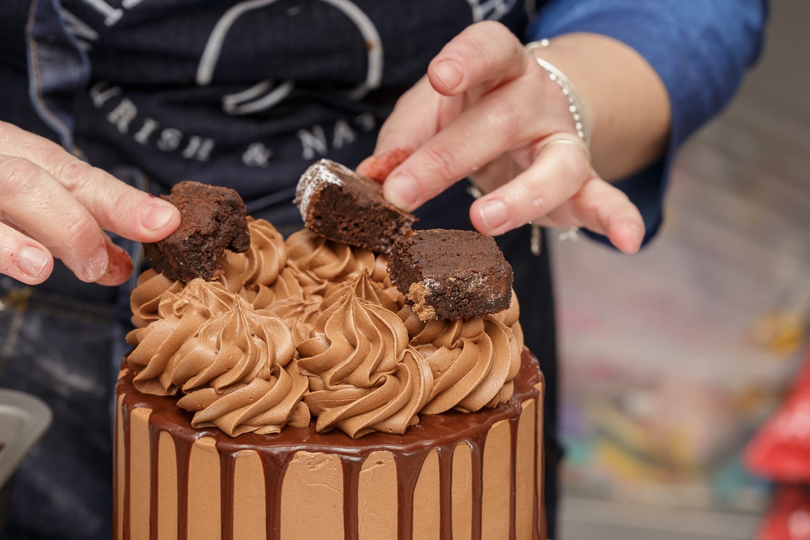 chocolate cake with brownie topping being added by baker