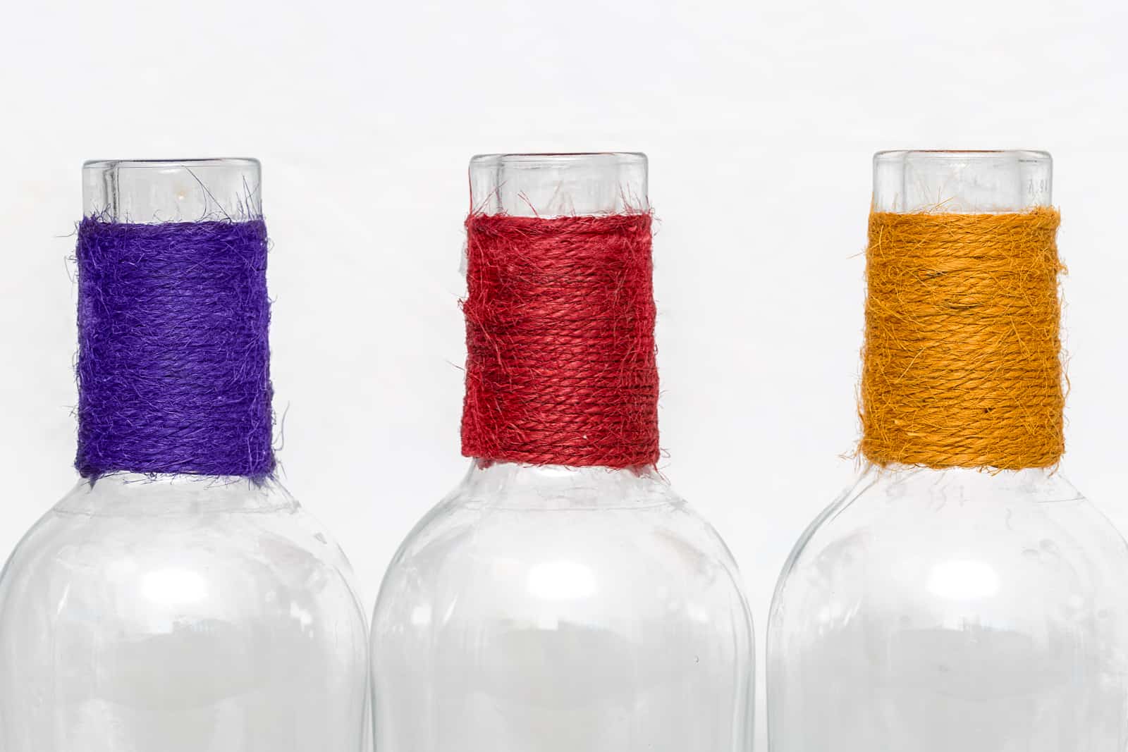 three empty gin bottles with coloured string tied around their necks