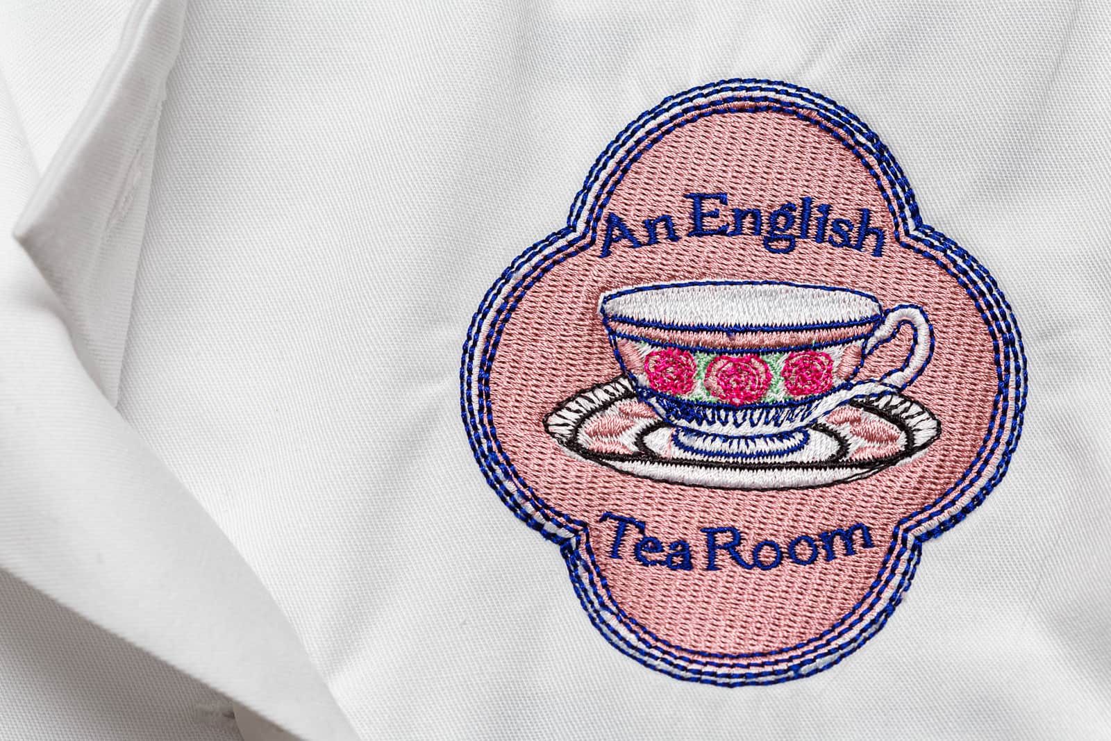 embroidered an english tea room logo on white overalls