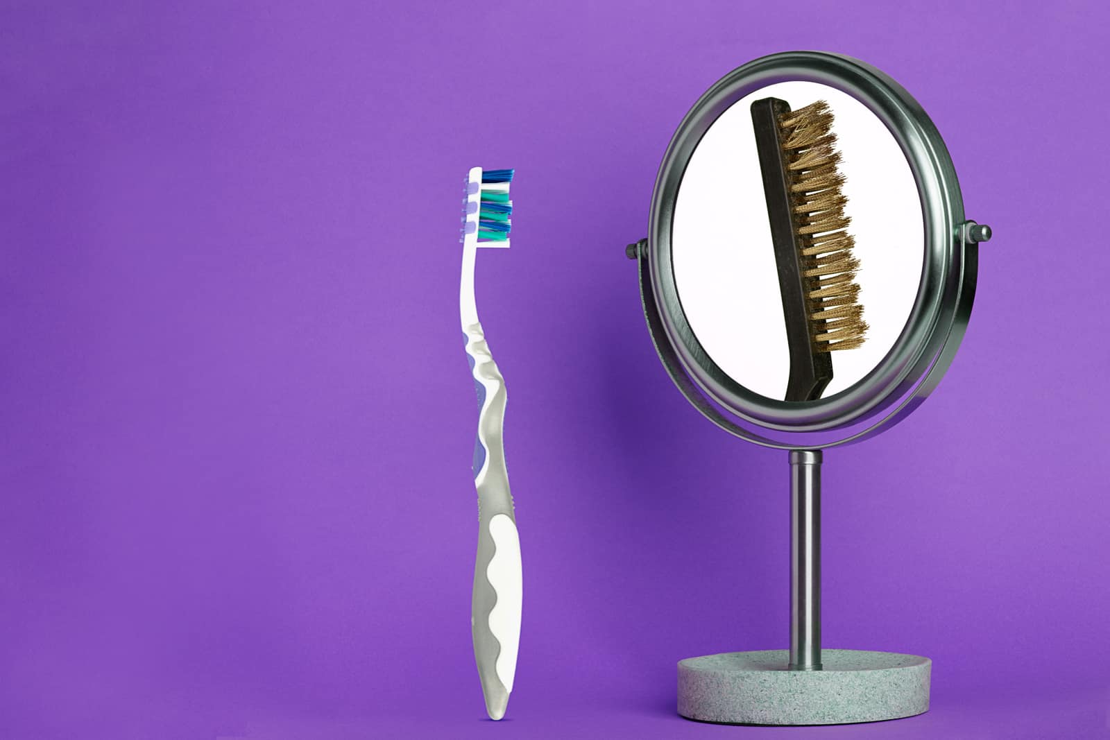 composite photograph of toothbrush and wire brush in mirror on purple background with copy space