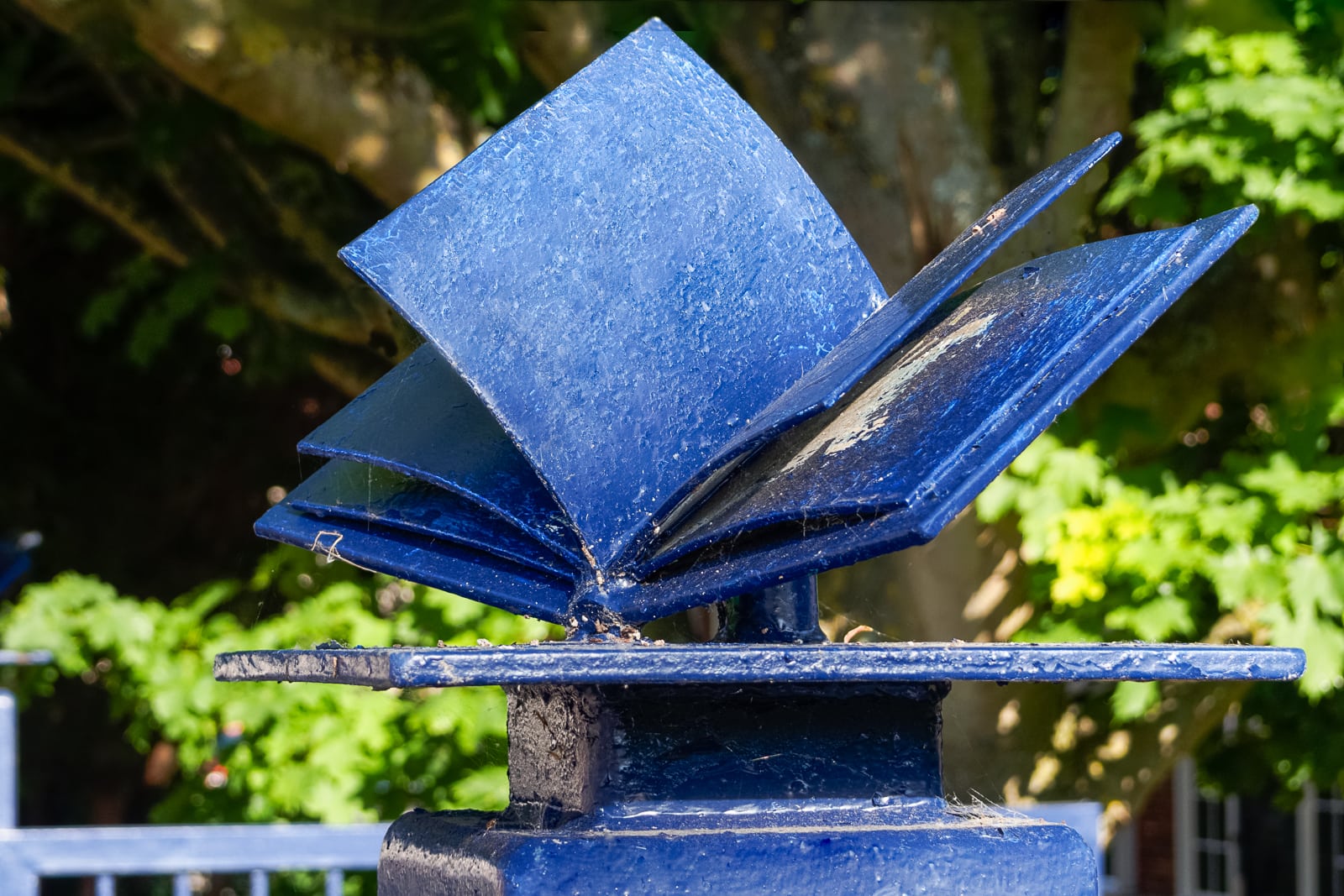 blue open book sculpture on school gate post